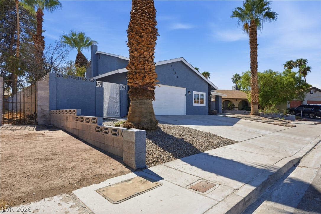 1707 Mapleton Lane, Las Vegas, NV 89119 Towering palm trees frame the concrete driveway and stucco exterior of this desert home.