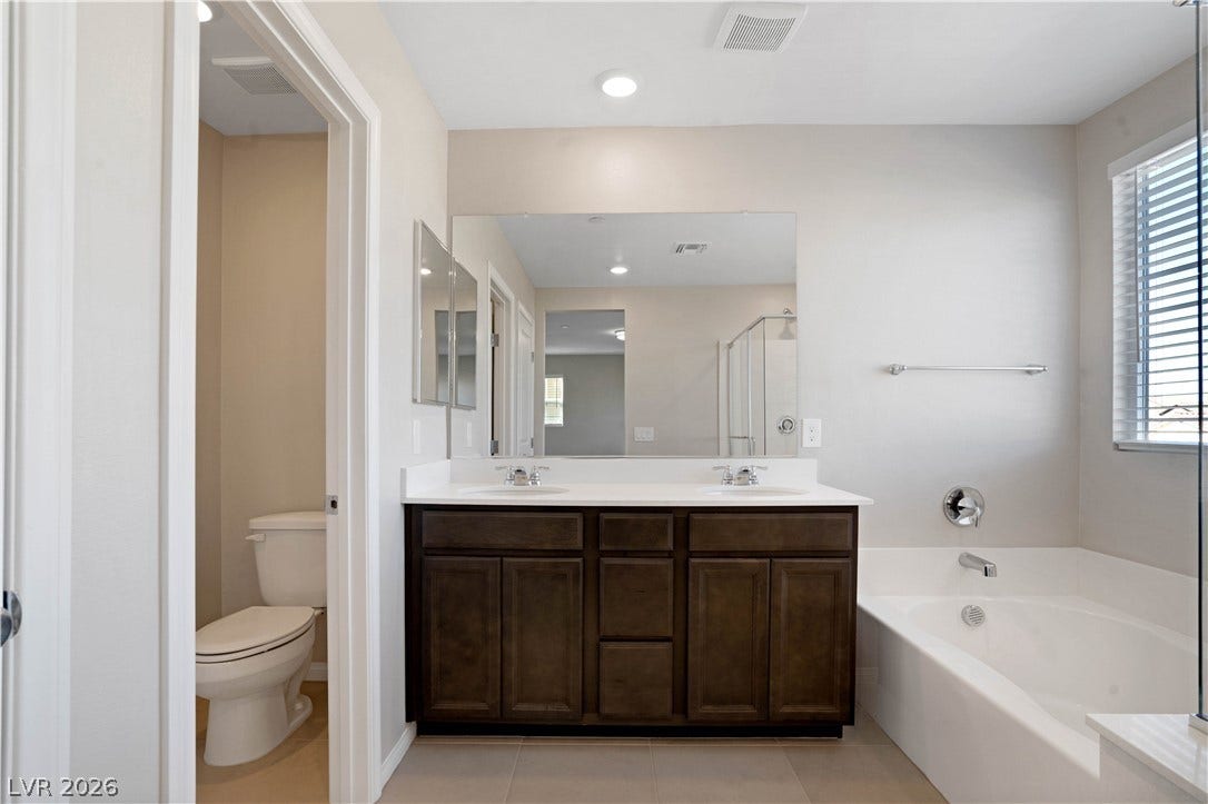 A well-appointed primary bathroom features a dual vanity, a soaking tub, and a private water closet