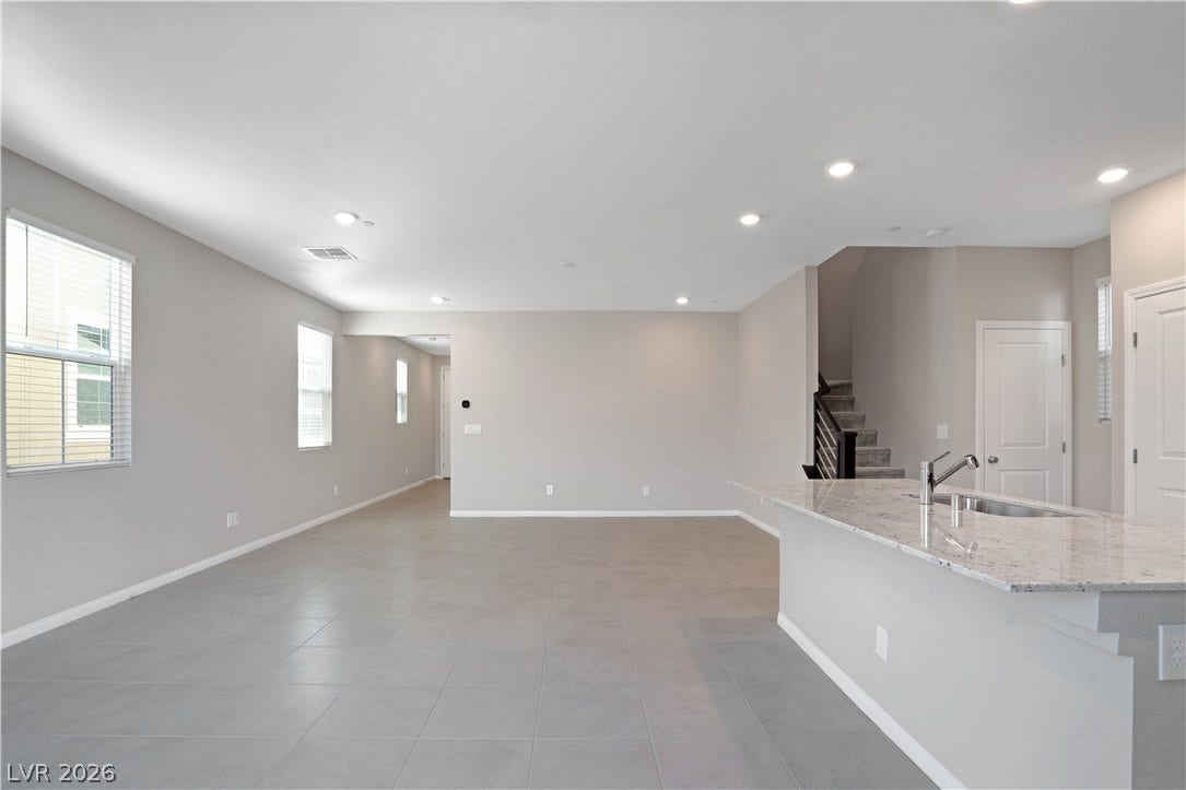 A spacious, open-concept living area with light tile flooring and modern recessed lighting