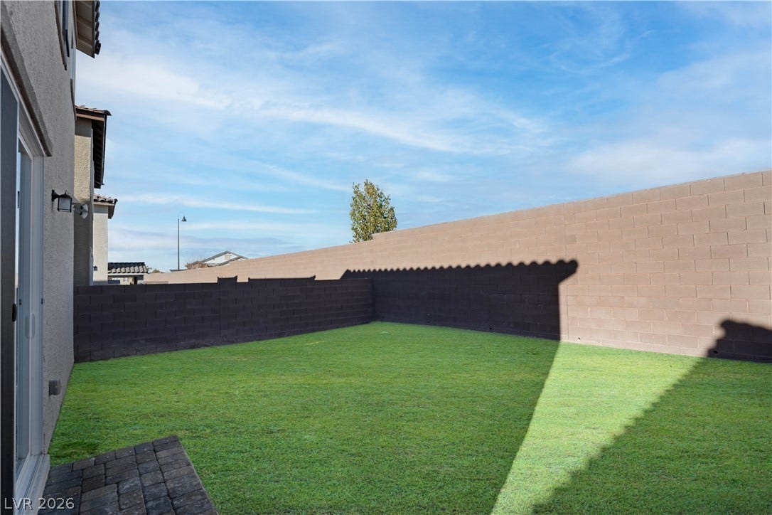 Virtual staged. Backyard now has a large paved patio, turf, various plants and small citrus trees