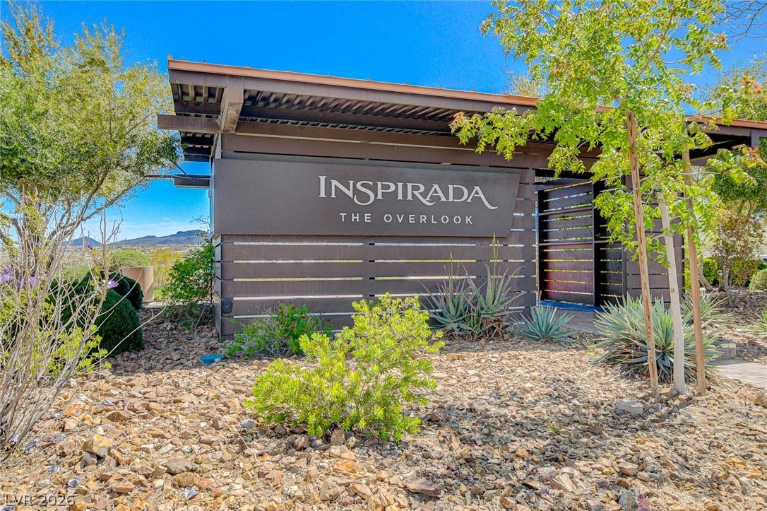 A welcoming entry sign for 'Inspirada The Overlook' set against a natural, rocky landscape with green desert plantings
