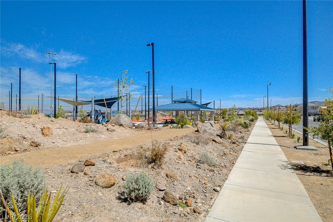 A community recreation area featuring covered picnic tables and a walking path