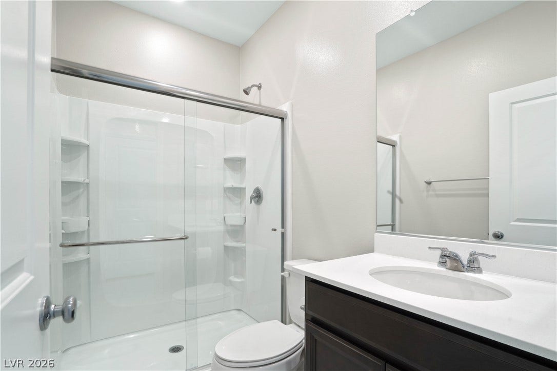A well-appointed bathroom downstairs with a clear glass shower enclosure and a dark wood vanity