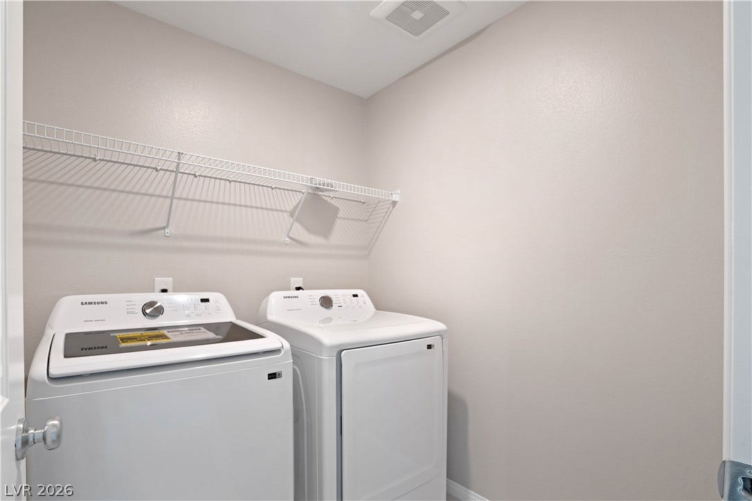 A dedicated laundry space provides essential convenience with modern appliances and practical overhead shelving