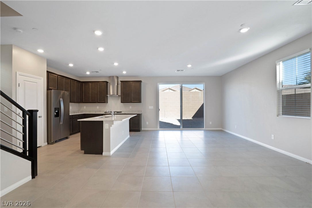 A spacious, open-concept living area with a kitchen island and sleek tile flooring