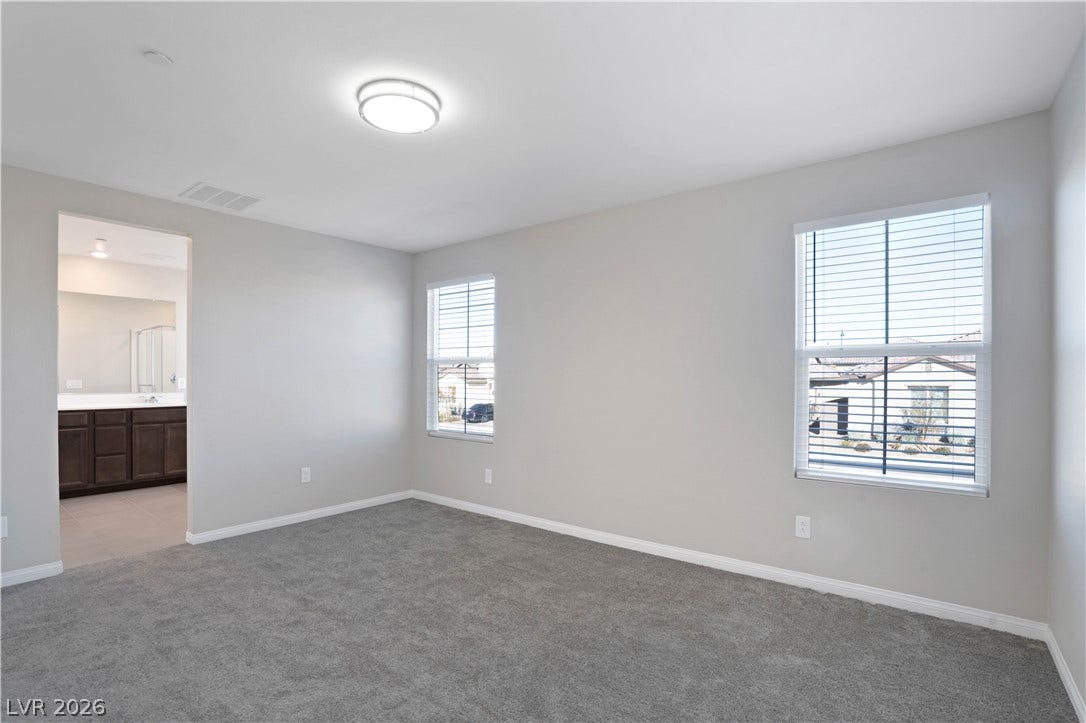 A well-lit bedroom features plush carpeting and convenient access to an en-suite bathroom