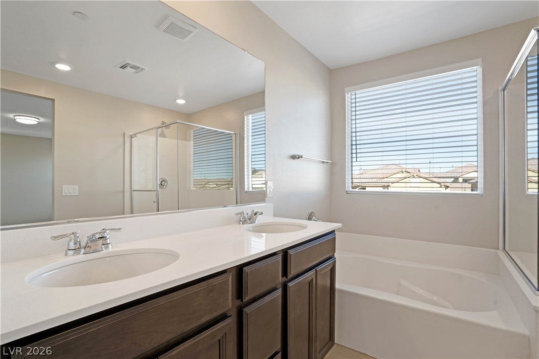 Dual vanity sinks complement a soaking tub and glass-enclosed shower in this bright bathroom