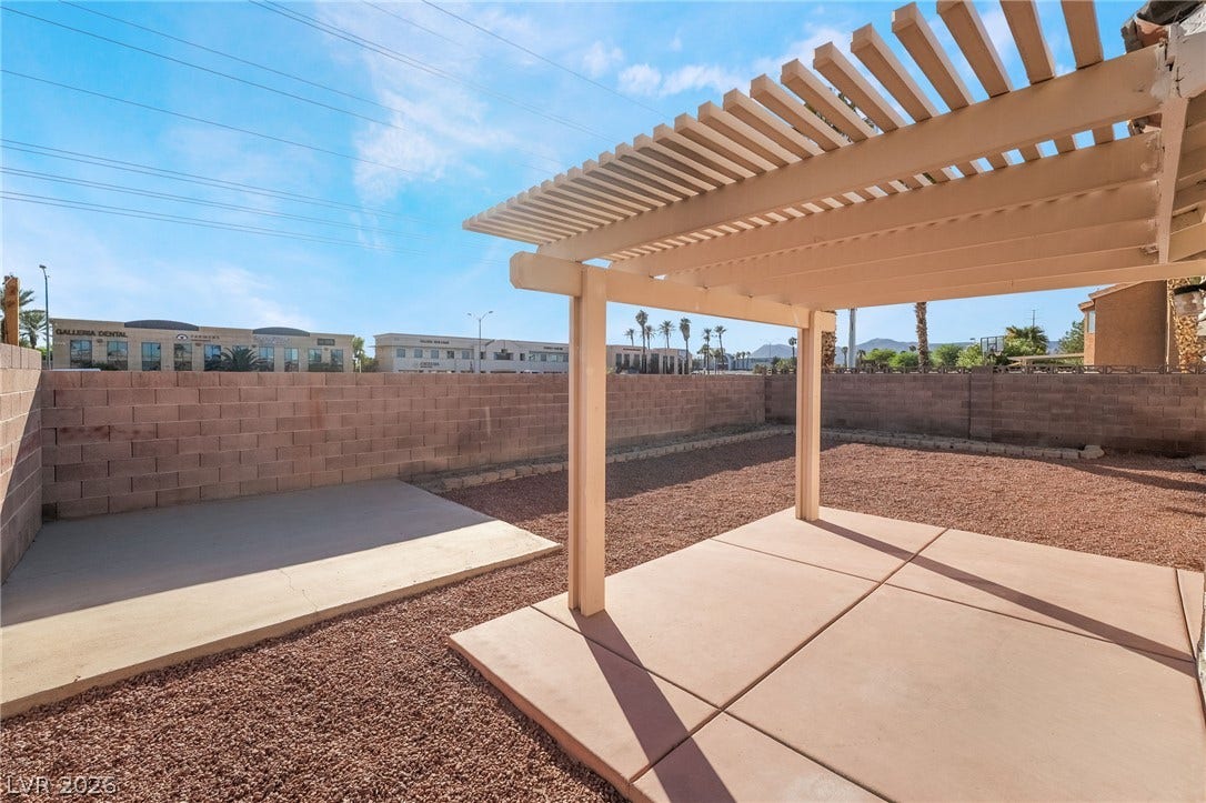 768 Panhandle Drive, Henderson, NV 89014 A spacious block-walled backyard features concrete patio areas shaded by a classic wood pergola.