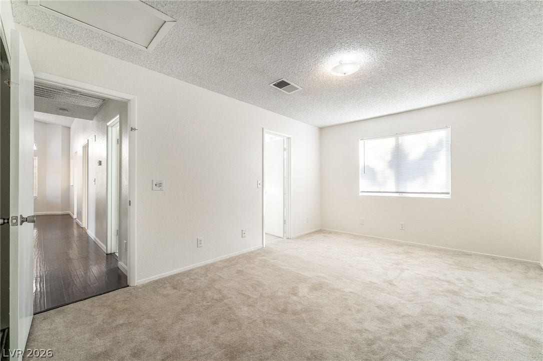 768 Panhandle Drive, Henderson, NV 89014 Soft carpeting underfoot defines this inviting bedroom featuring a large window and adjoining hallway.