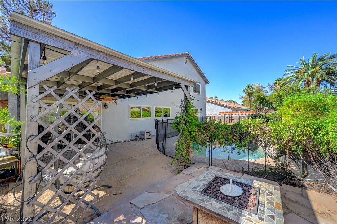 342 Fuente Drive, Henderson, NV 89014 A spacious concrete patio under a wooden pergola overlooks the fenced backyard pool.