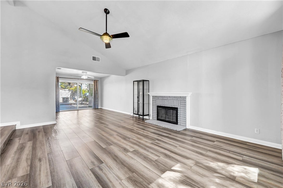 342 Fuente Drive, Henderson, NV 89014 Vaulted ceilings and wood-look flooring enhance this spacious living area with a brick fireplace.