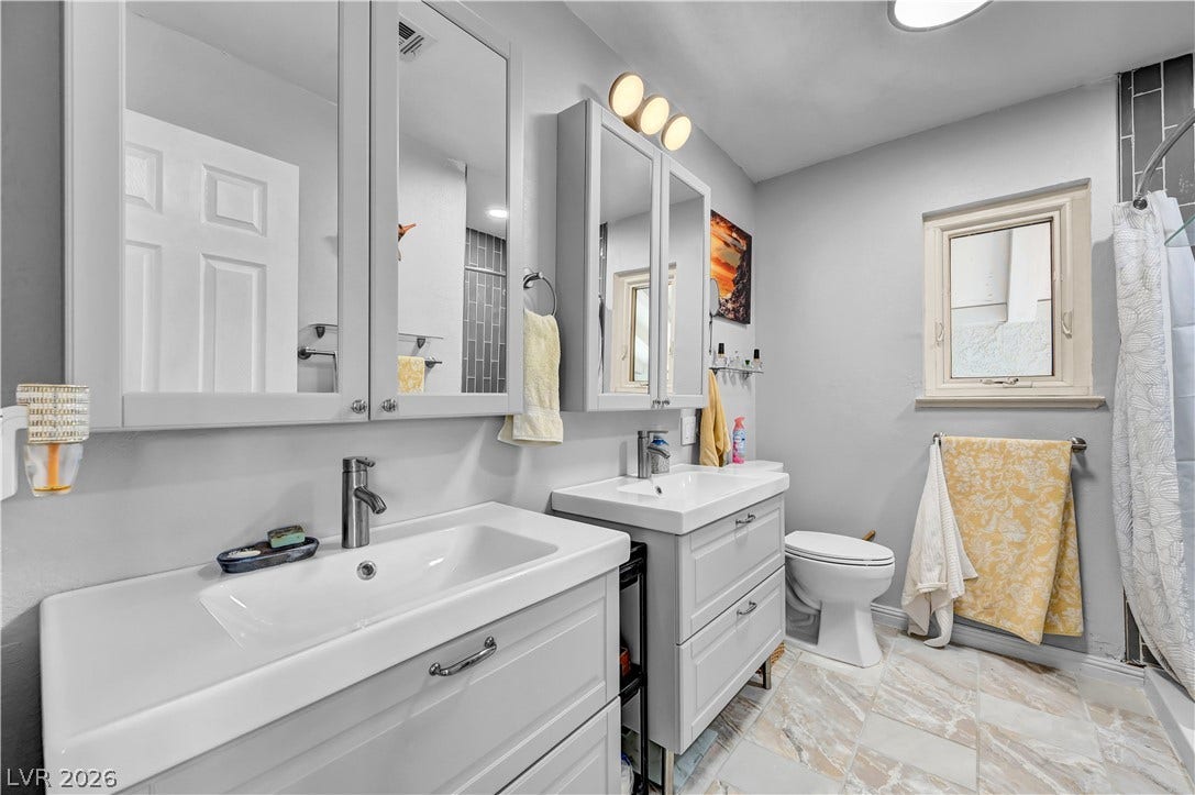 342 Fuente Drive, Henderson, NV 89014 Double vanities with white integrated sinks sit on marble-patterned tile flooring.
