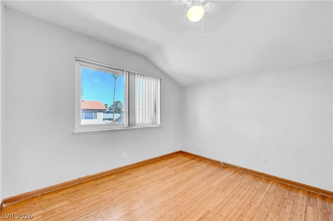 342 Fuente Drive, Henderson, NV 89014 Warm wood flooring and vaulted ceilings shape this inviting bedroom space.