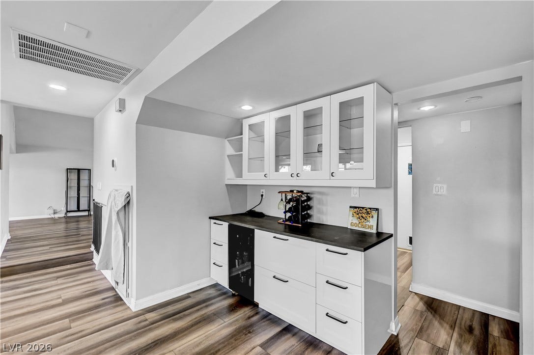 342 Fuente Drive, Henderson, NV 89014 Glass-front upper cabinets and durable wood-look flooring anchor this sleek modern dry bar space.