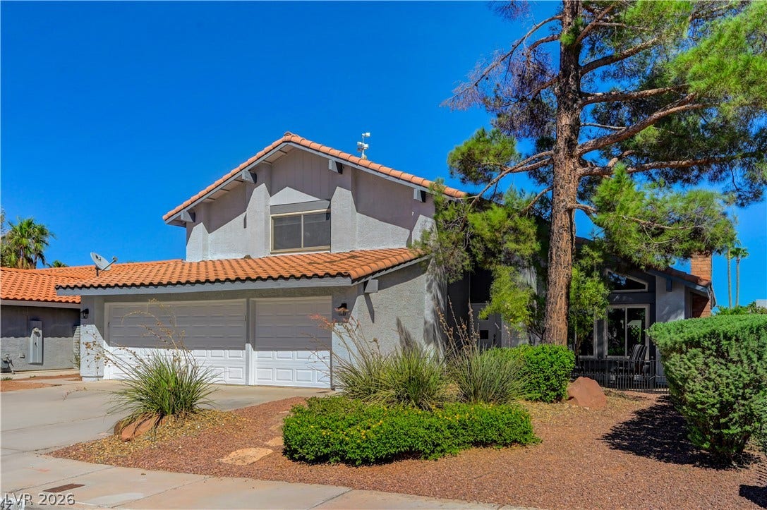 342 Fuente Drive, Henderson, NV 89014 Mature trees shade a classic two-story exterior featuring a clay tile roof and a two-car garage.