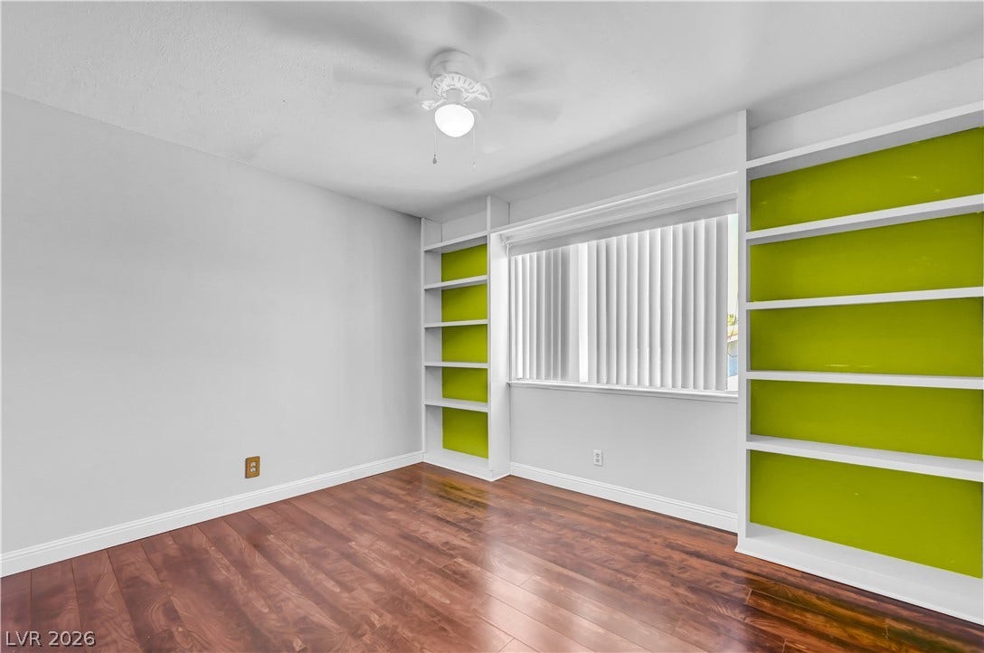 342 Fuente Drive, Henderson, NV 89014 Polished hardwood flooring and custom built-in shelving frame a bright window in this versatile space.