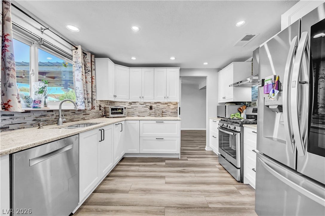 342 Fuente Drive, Henderson, NV 89014 Gleaming stone countertops and stainless steel appliances elevate this bright, functional culinary space.