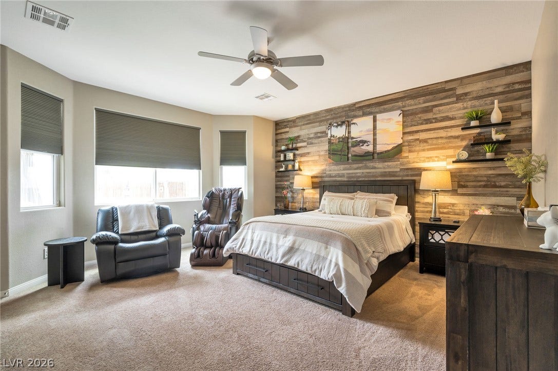 5652 Portage Lake Court, Las Vegas, NV 89130 Relax in this tranquil bedroom, featuring an inviting bay window area and rustic wood paneling.