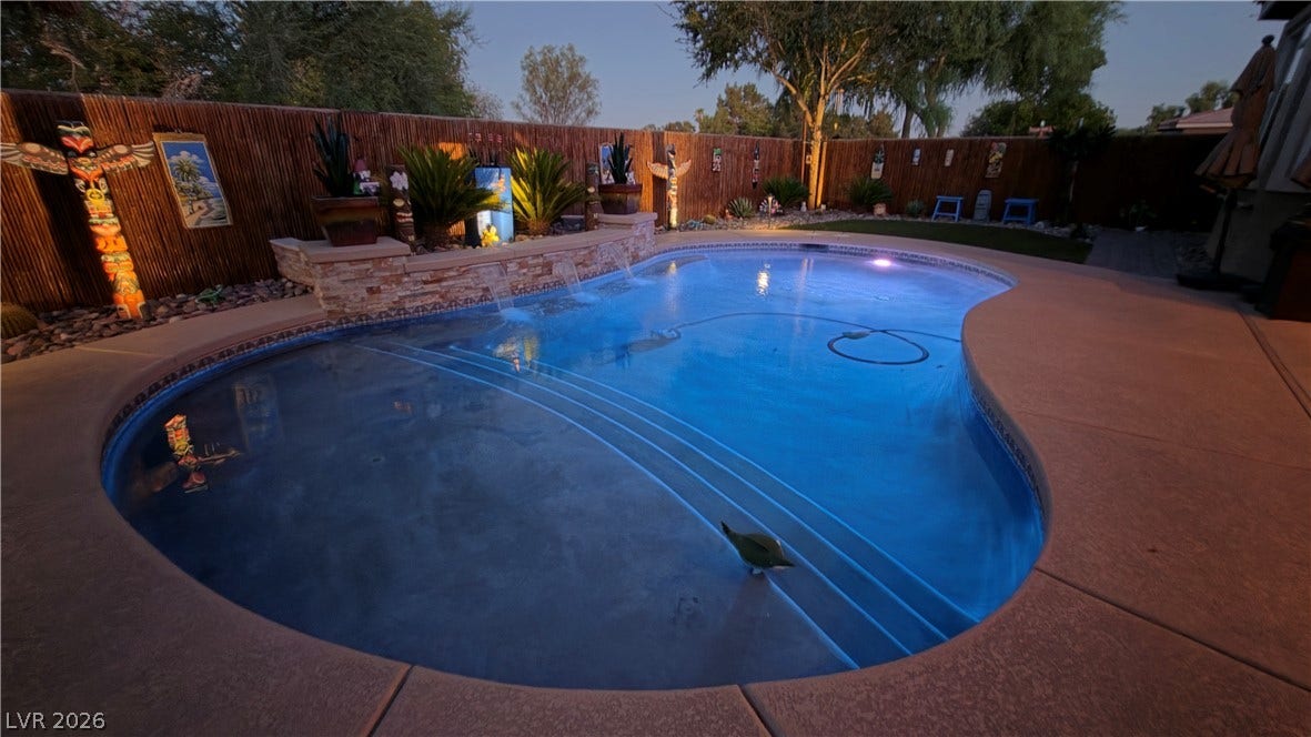 5652 Portage Lake Court, Las Vegas, NV 89130 An inviting backyard oasis offers a free-form pool with illuminated steps and a decorative stone waterfall feature.