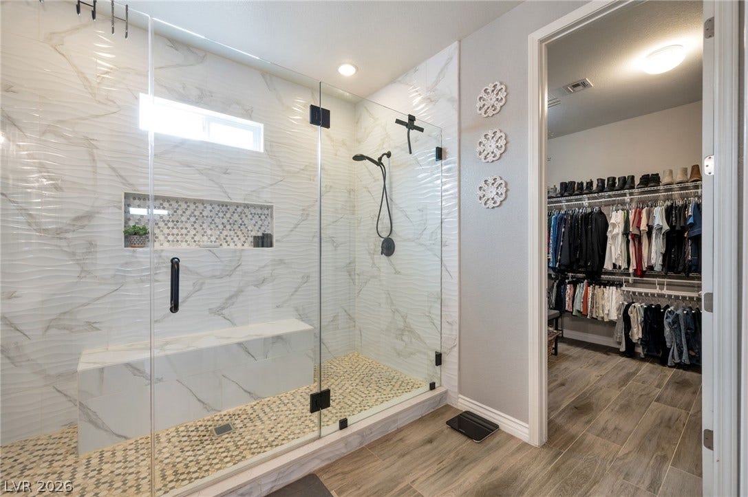 5652 Portage Lake Court, Las Vegas, NV 89130 Luxurious walk-in shower with a mosaic tile floor, built-in bench, and adjacent spacious closet.