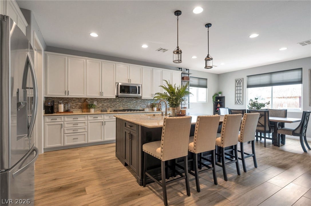 5652 Portage Lake Court, Las Vegas, NV 89130 A well-lit kitchen with sleek stainless steel appliances, a spacious island, and wood-look flooring.