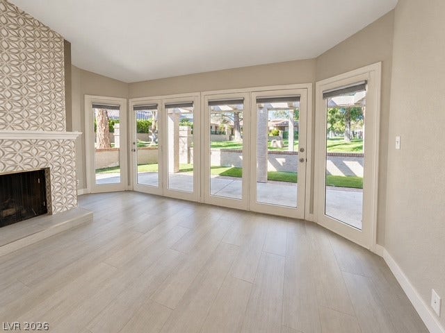 A tiled fireplace and light wood floors ground this airy room lined with glass doors.