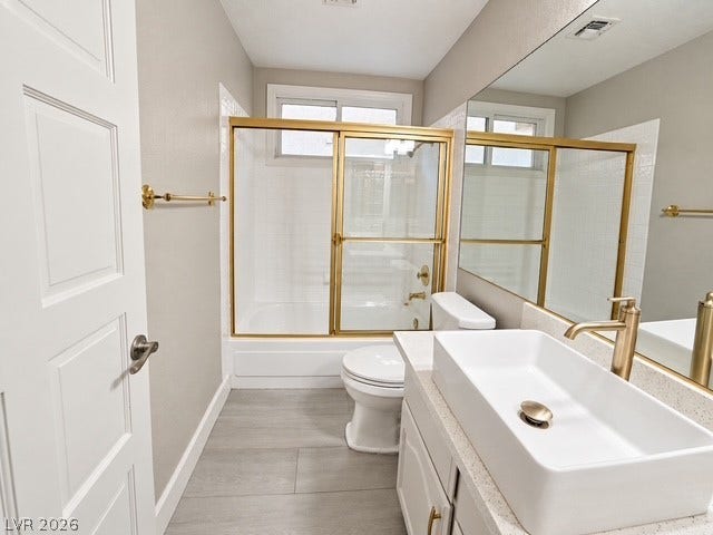 Gleaming gold fixtures elevate this updated bathroom space with its modern vessel sink setup.