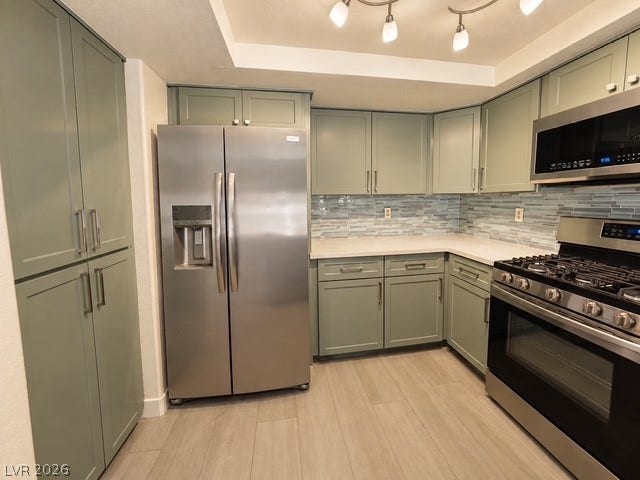Gleaming stainless steel appliances complement the custom cabinetry and tiled backsplash in this modern kitchen.