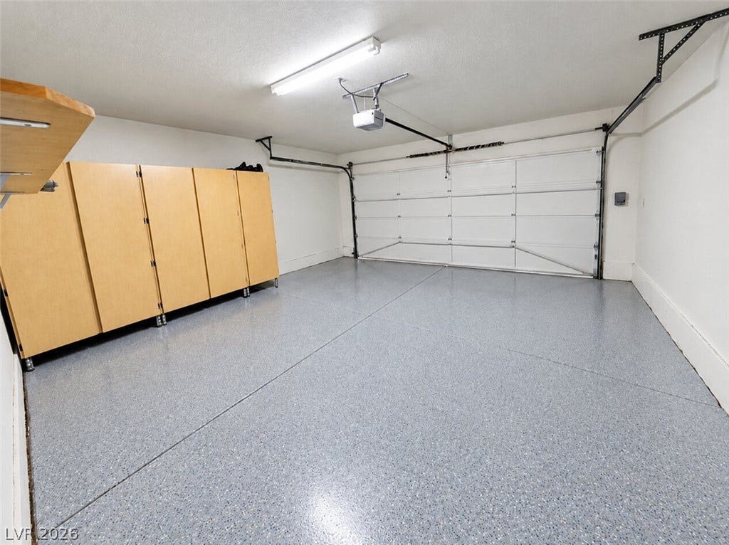 Ample storage cabinetry lines this clean two-car garage featuring sealed concrete flooring.