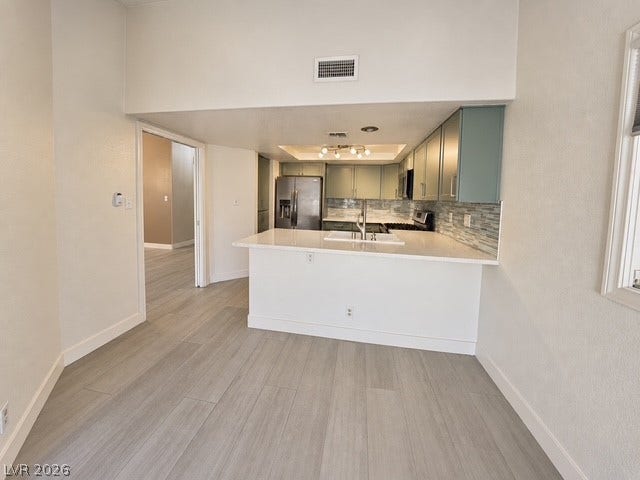 Gleaming wood-look floors flow into a modern kitchen complete with solid counters and stainless appliances.