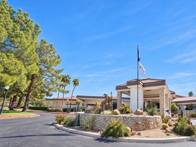 A grand stone-accented porte-cochere welcomes arrivals under wide blue desert skies.