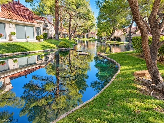 Mature trees frame a peaceful water feature winding past elegant tiled-roof townhomes.