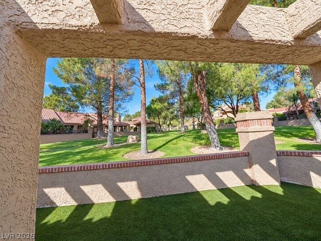 Mature trees and a manicured greenbelt frame the view from this shaded patio space.