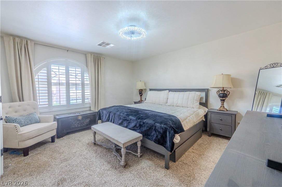 6007 Sonoma Station Avenue, Las Vegas, NV 89139 An arched window frames natural light across a carpeted bedroom with smooth plaster walls.