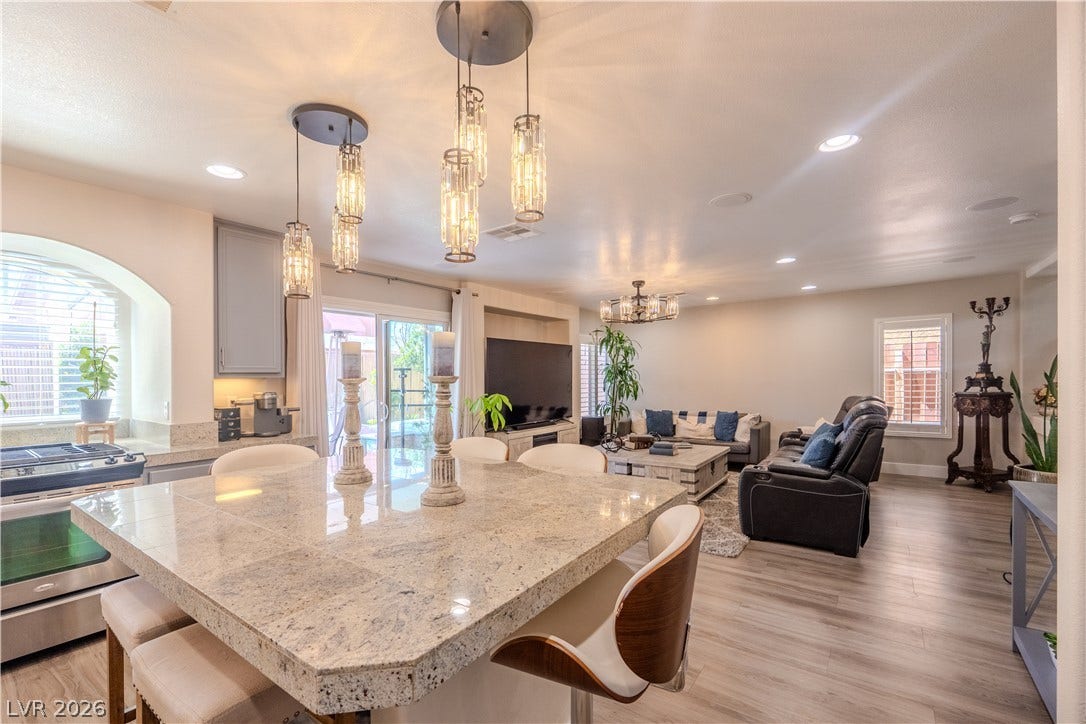 6007 Sonoma Station Avenue, Las Vegas, NV 89139 Gleaming stone countertops and wood flooring define this open-concept kitchen and living area.