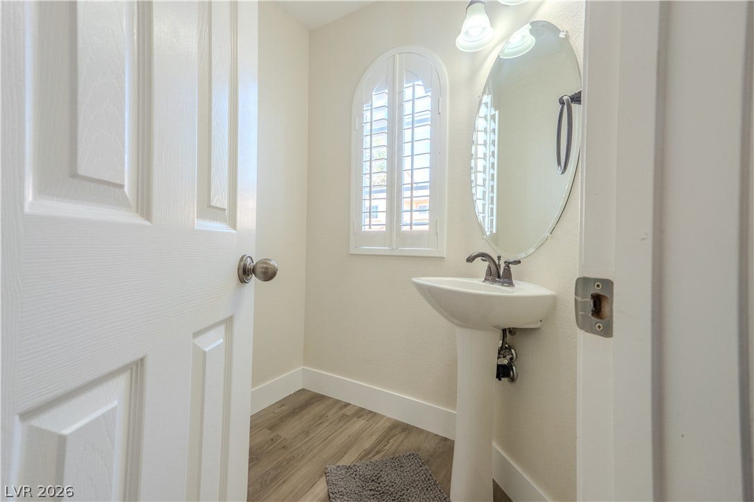 6007 Sonoma Station Avenue, Las Vegas, NV 89139 An elegant arched window with shutters anchors this classic powder room featuring durable wood-look flooring.