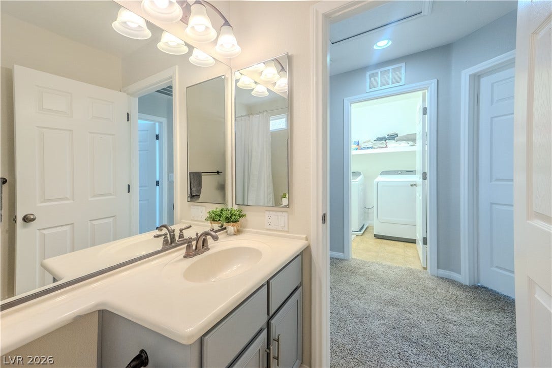 6007 Sonoma Station Avenue, Las Vegas, NV 89139 An open doorway links the vanity space directly to a carpeted hall and laundry room.
