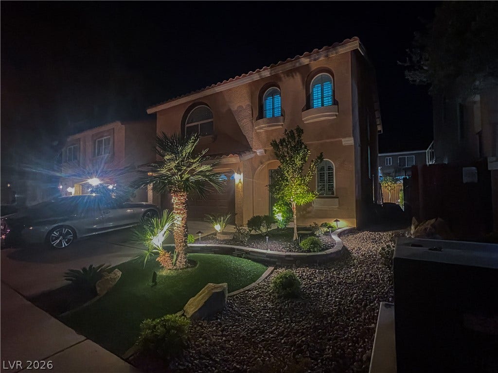 6007 Sonoma Station Avenue, Las Vegas, NV 89139 Dramatic night lighting showcases the elegant arched windows and manicured desert landscaping of this two-story home.