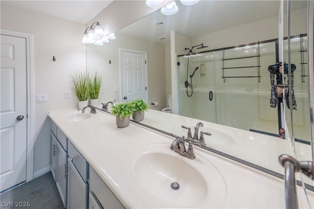 6007 Sonoma Station Avenue, Las Vegas, NV 89139 A spacious vanity with integrated dual sinks and a large mirror sits on vinyl flooring.