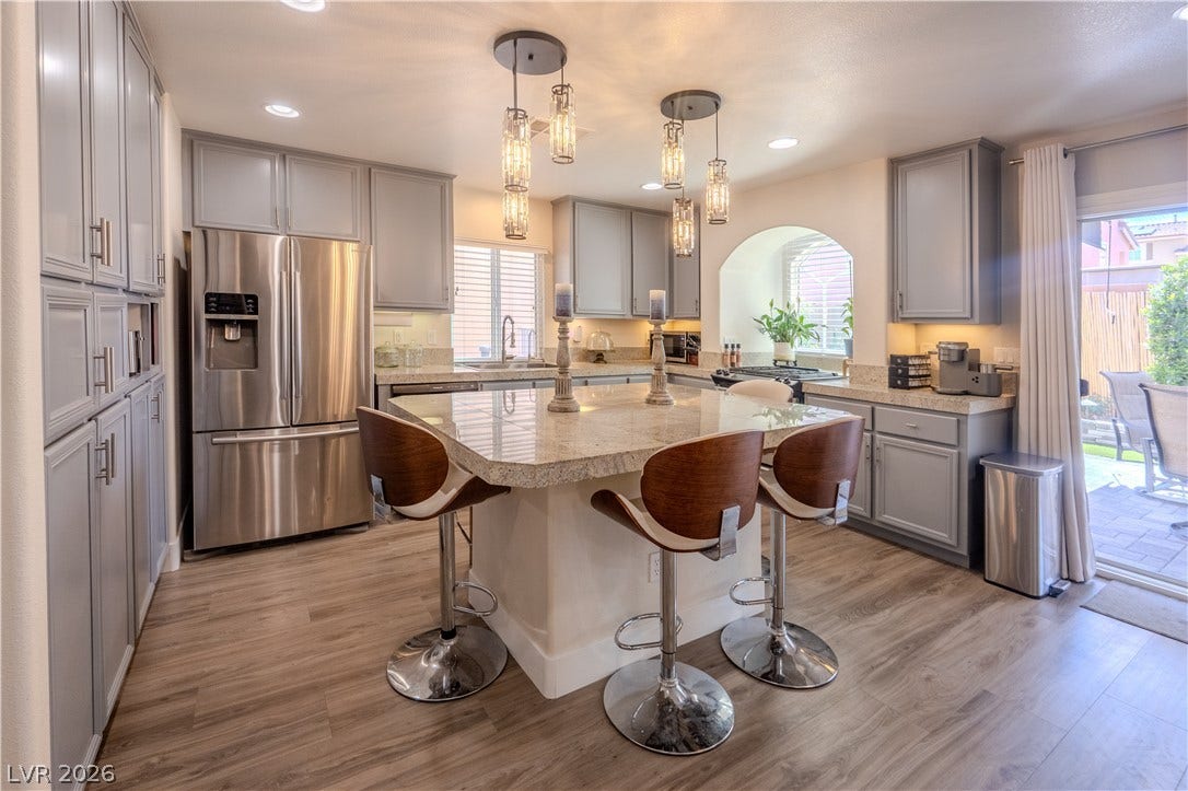 6007 Sonoma Station Avenue, Las Vegas, NV 89139 Gleaming stone countertops and a generous central island anchor this beautifully appointed kitchen space.