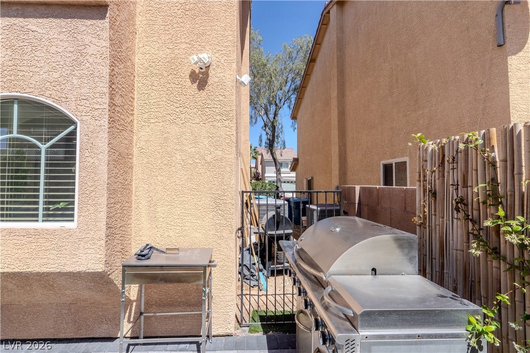 6007 Sonoma Station Avenue, Las Vegas, NV 89139 Stucco exteriors frame a paved side yard featuring a built-in outdoor grill area.