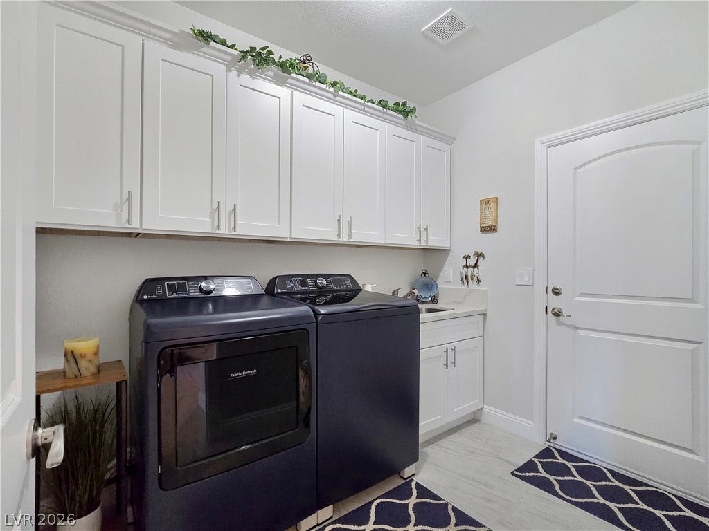 5471 Lincolnwood Court, Pahrump, NV 89061 Abundant overhead cabinetry and a practical utility sink elevate this dedicated laundry space.