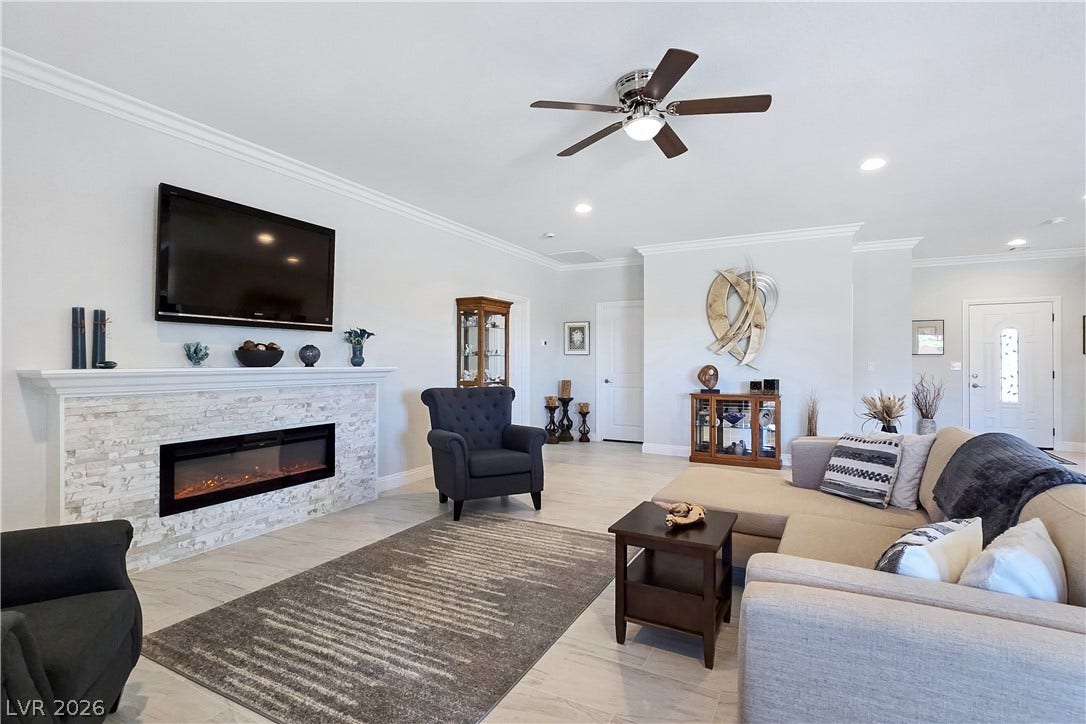 5471 Lincolnwood Court, Pahrump, NV 89061 Crown molding frames the open-concept living area highlighting a stone-clad fireplace and tile flooring.