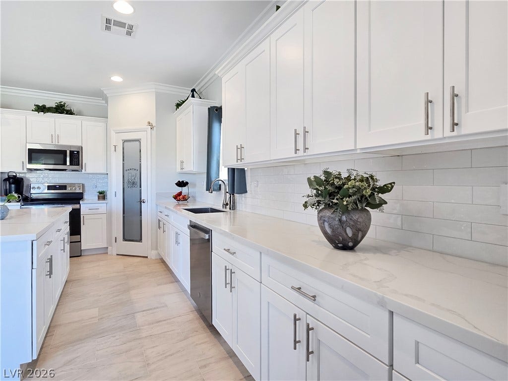5471 Lincolnwood Court, Pahrump, NV 89061 Polished stone countertops pair elegantly with clean white cabinetry and classic tiled backsplashes.