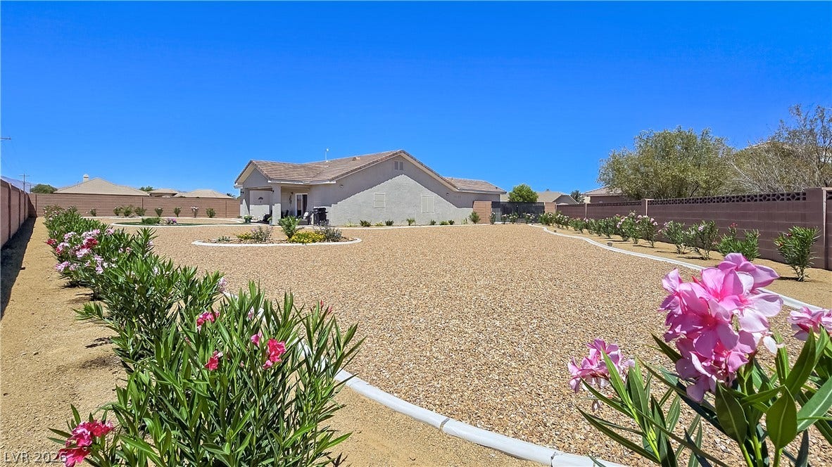 5471 Lincolnwood Court, Pahrump, NV 89061 An expansive gravel yard features structured garden beds enclosed by block walls.