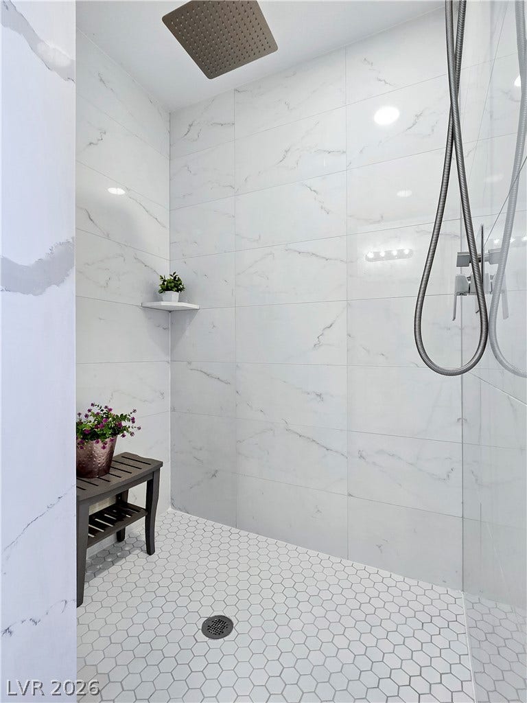 5471 Lincolnwood Court, Pahrump, NV 89061 Floor-to-ceiling marble-look wall tiles surround a modern walk-in shower with sleek fixtures.