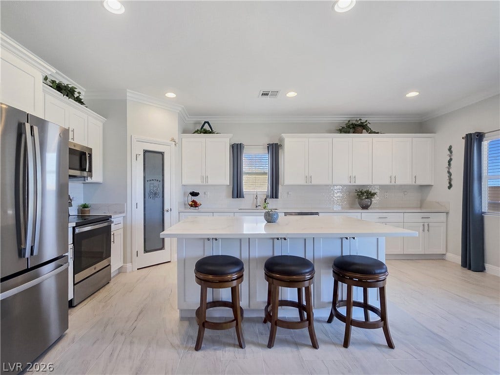 5471 Lincolnwood Court, Pahrump, NV 89061 Gleaming stone countertops and a spacious central island anchor this light-filled culinary space.