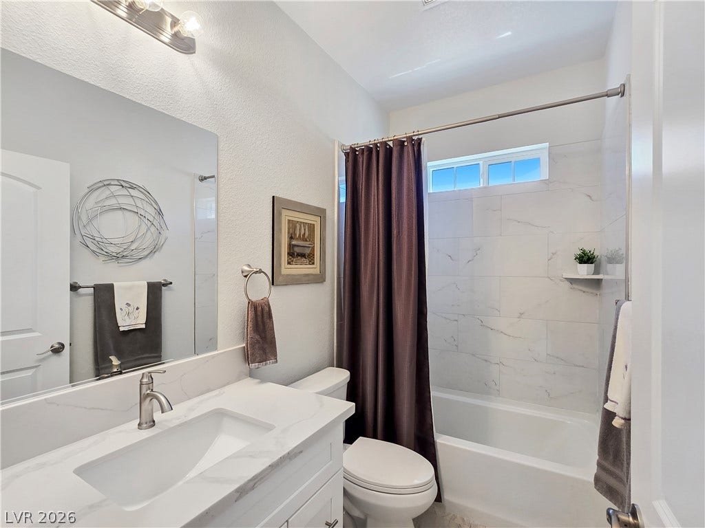 5471 Lincolnwood Court, Pahrump, NV 89061 Clean lines and stone counters define this modern bathroom with its tiled shower and tub.
