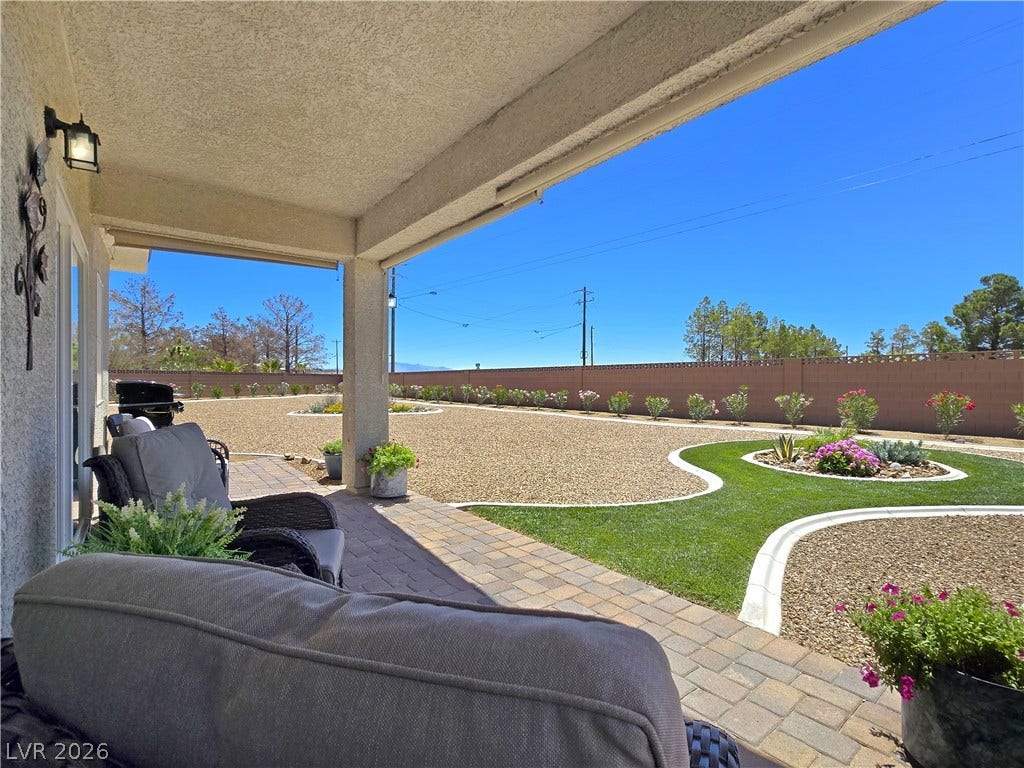 5471 Lincolnwood Court, Pahrump, NV 89061 A covered patio opens to a beautifully landscaped yard featuring meticulous stone pavers and lush greenery.