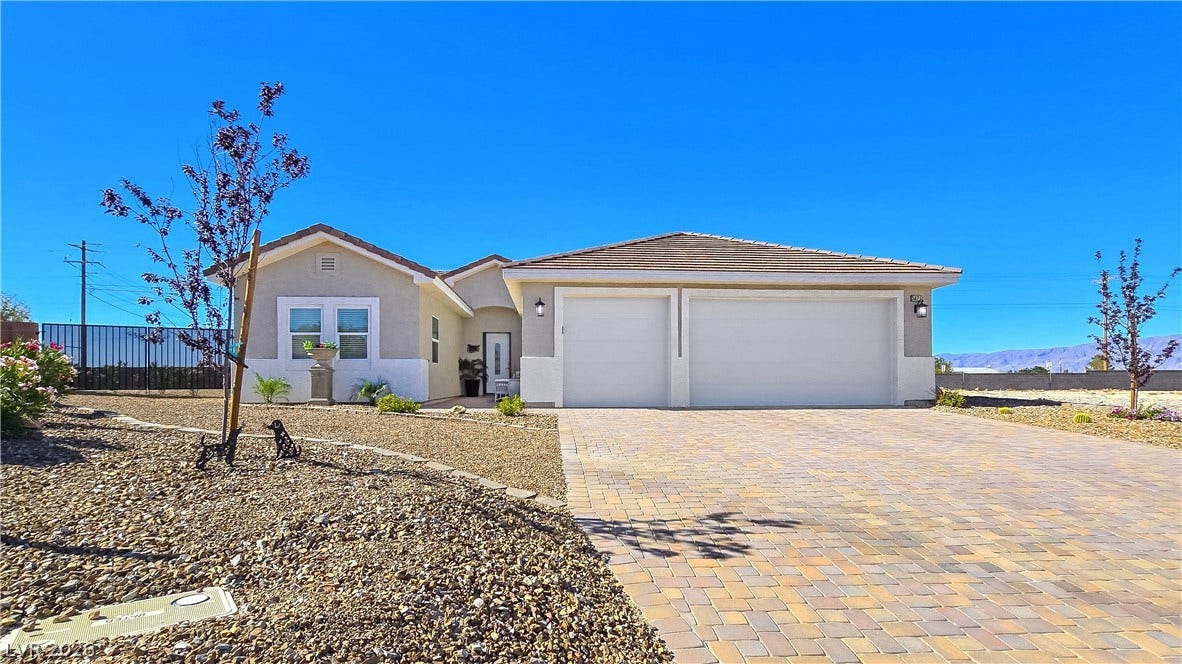 5471 Lincolnwood Court, Pahrump, NV 89061 An inviting stone driveway leads to a modern single-story residence under clear blue skies.